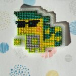 Ajaw brodé. Personnage reptilien vert et jaune avec des lunette de soleil cool.